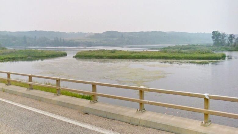 A river is surrounded by forest is seen from a bridge. Big Knife Provincial Park, seen from the Highway 855 bridge, straddles the Battle River and is a mix of grasslands and forest.