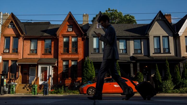 Person in shadow walking in front of a row of homes.