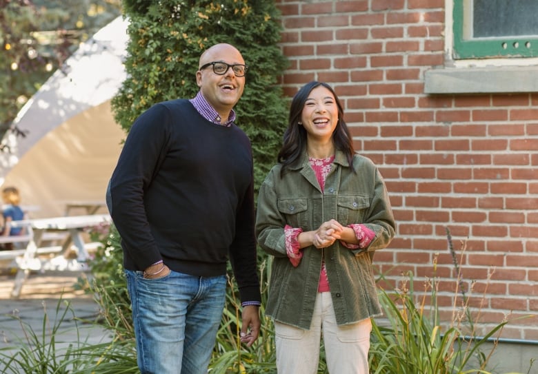 Two people standing next to a brick building.