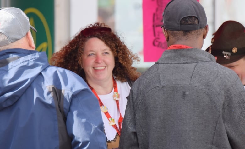 Woman facing camera is seen smiling at man who is facing her.