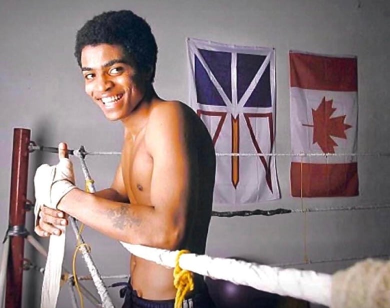 Smiling young man in boxing gear in the ring. 