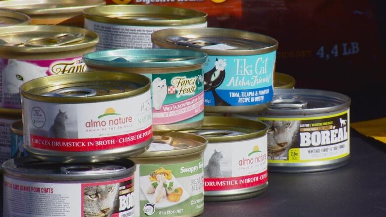 A stack of tinned cat food sits on a table