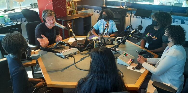 A group of people sitting around a desk talking into mics