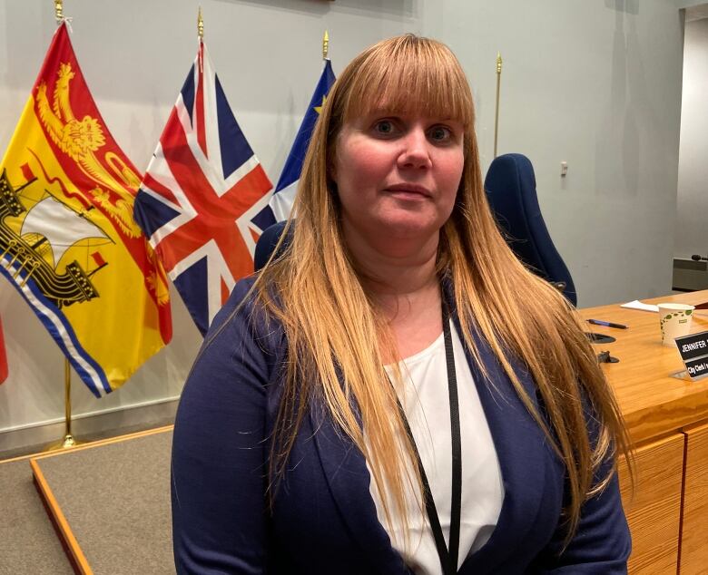 Fredericton city treasurer Alicia Keating stands in council chambers with flags in the rear. 