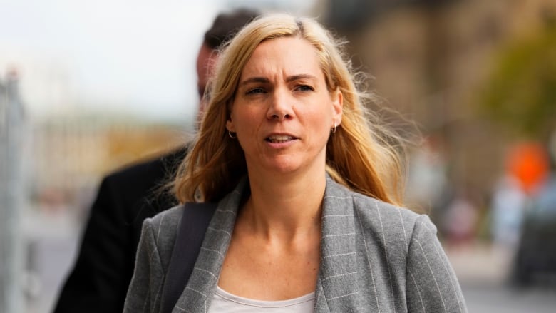 A mid-shot of a blonde woman wearing a grey blazer.