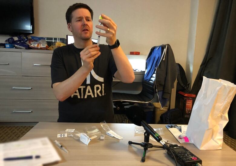 A man is preparing a needle, with a tape recorder on the table.