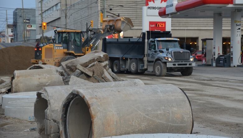 Large chunks of cement and a pile of sand sit on Algonquin Boulevard in Timmins near the landmark Senator hotel, while a loader dumps sand into a dump truck.