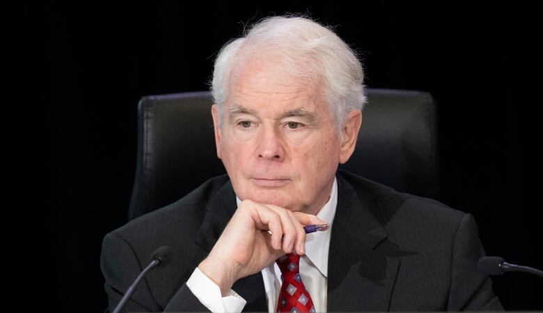 A man in a suit and tie listens at a desk.