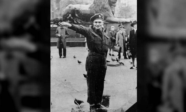 Old-looking photograph of uniformed man holding arm out, bird in hand. A crowd is behind him.