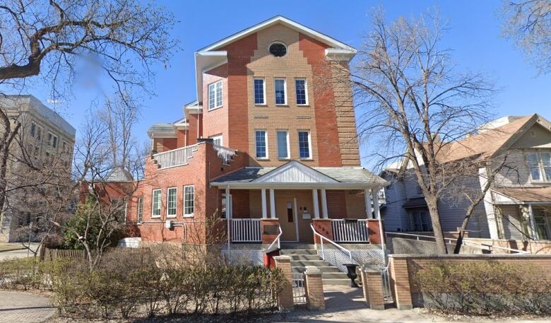 Tan three-storey house with white paneling. 