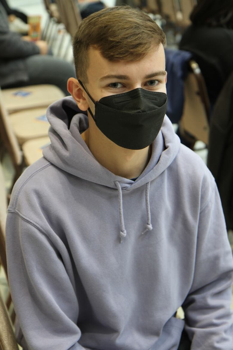 Caleb Smolenaars sits at the mayoral debate while masked.