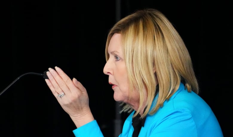 A woman gestures at a microphone.