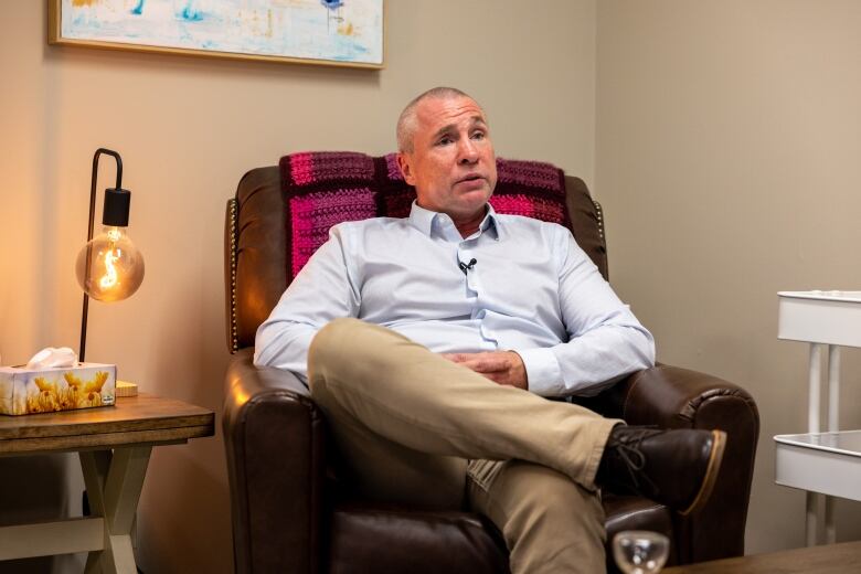 A man sits in a brown leather armchair