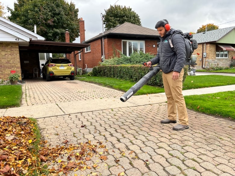 Ali is shown using a gas-powered leaf blower to clear a driveway.