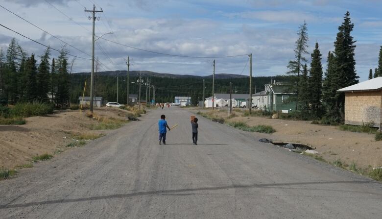 Two little boys are back on to the camera with homes and buildings in the background. 