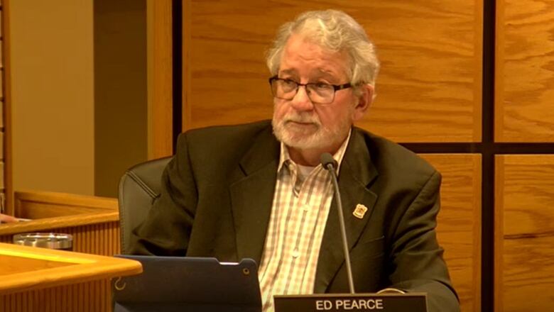 Ed Pearce sits at the Elliot Lake council table with a plaque bearing his name in front of him. 