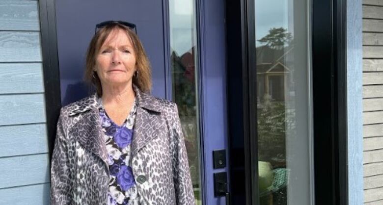 A woman stands outside a house