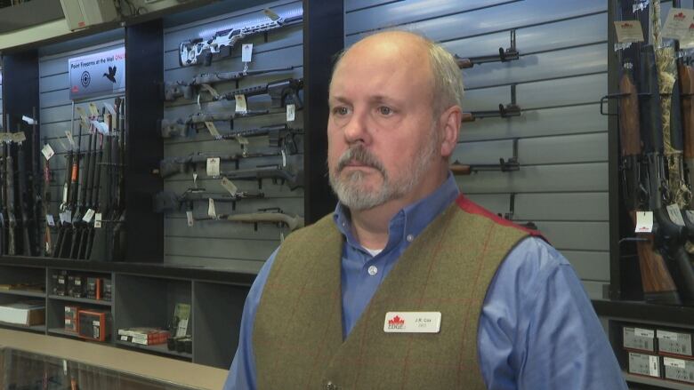 a photo of JR Cox in front of a wall with guns