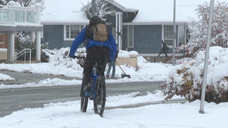 A person rides their bike through heavy snow.