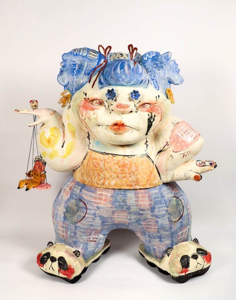 Photo of a ceramic form of a pudgy child with blue pigtails and panda slippers.