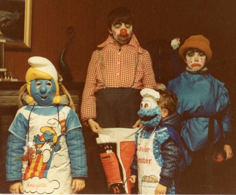 A group of four children in an old colour picture  one dressed as a Smurf, one as Cookie Monster, and two as clowns.