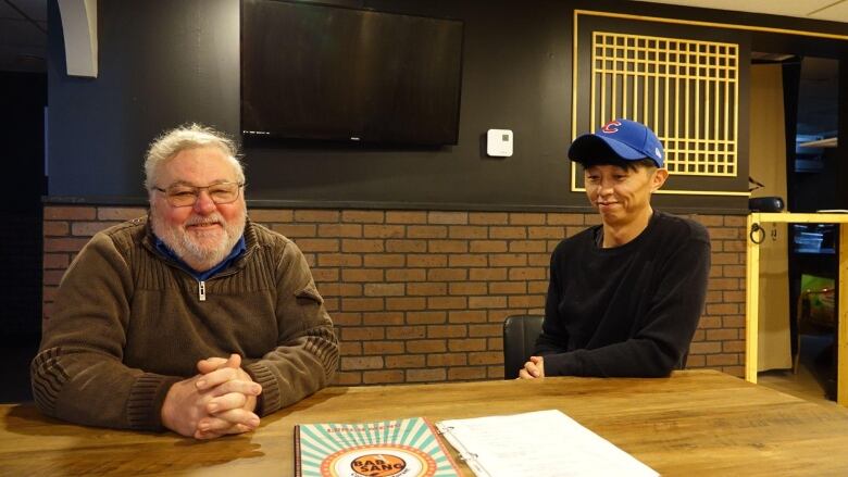 two people sit at a table, smiling