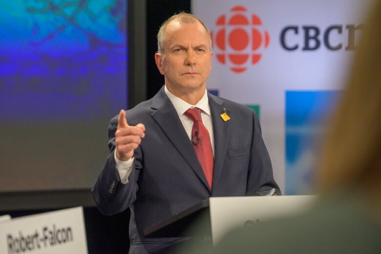 A man in a suit stands at a podium.