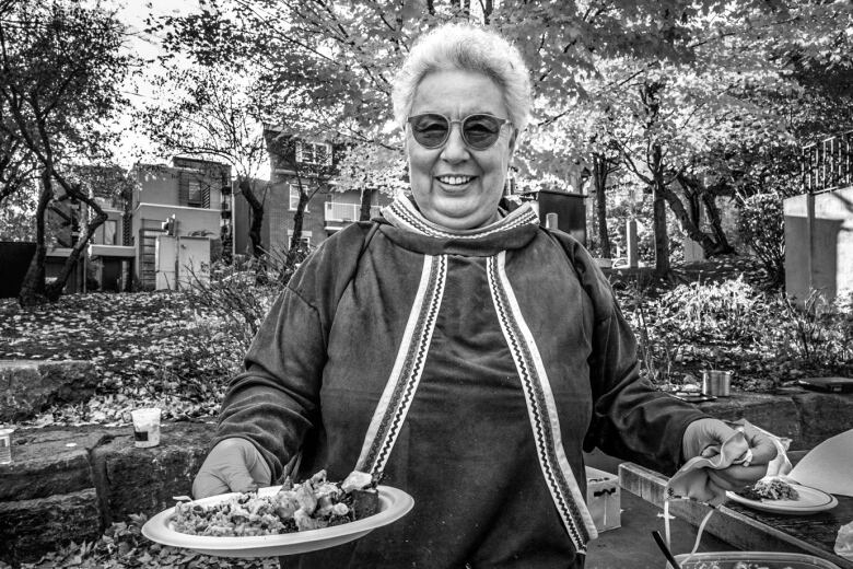 Woman stands smiling holding a plate of food