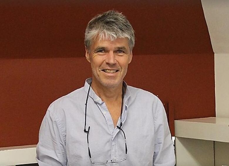 man with grey hair in front of red background