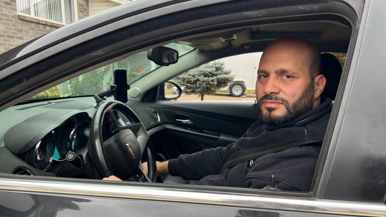 Man sits in his car looking out the window. 