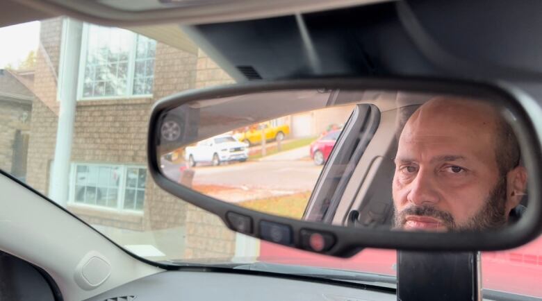 Picture of man's face in a car's rearview mirror. 