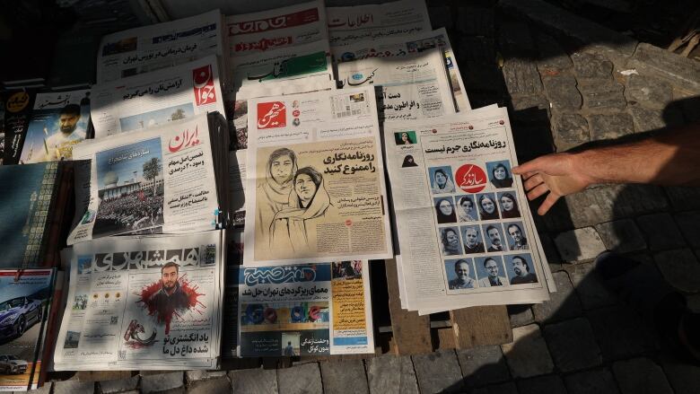 Several Iranian newspapers laid out on the ground.