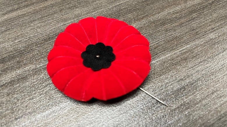 A close of of a red poppy pin that looks like the felt one.