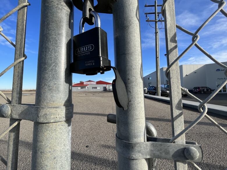 A locked gate in front of a red and grey building 