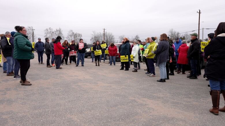 A group of people wearing winter coats hold signs that say 