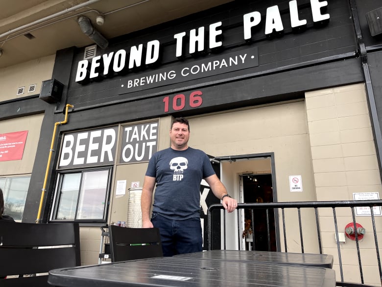 A man stands on a patio outside of a store.