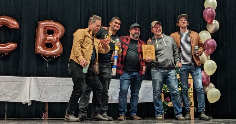 A group of white men smile on a stage.