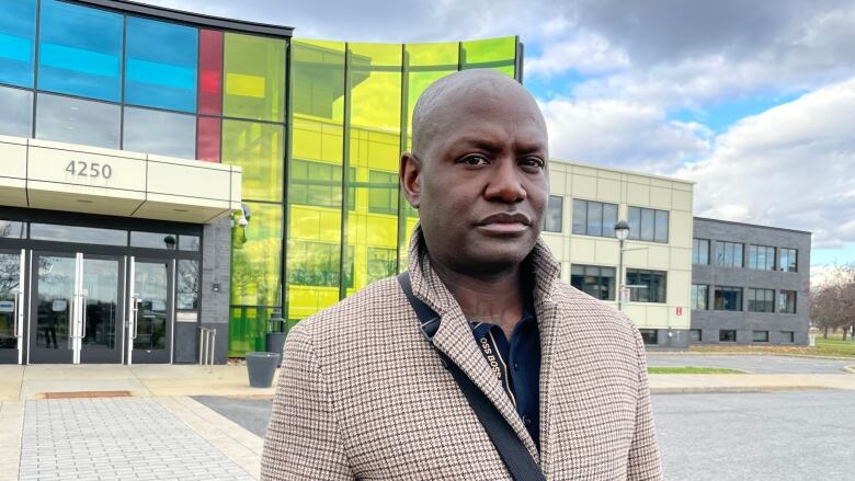 A man stands in front of a colourful building.