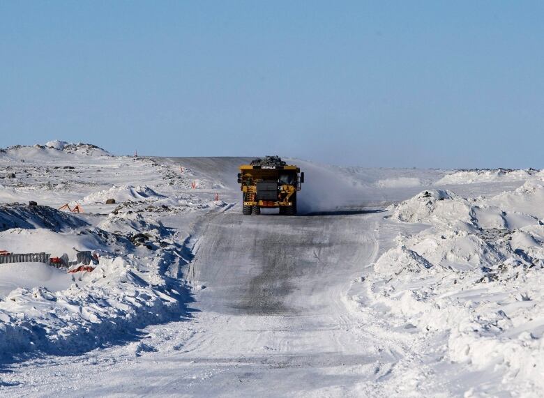 A mine haul truck drives down a snowy road.