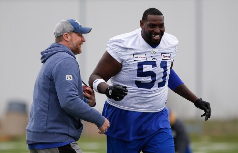 Winnipeg Blue Bombers head coach Mike O'Shea jokes around with Jermarcus Hardrick (51) during practice at training camp in Winnipeg Thursday, May 19, 2022.