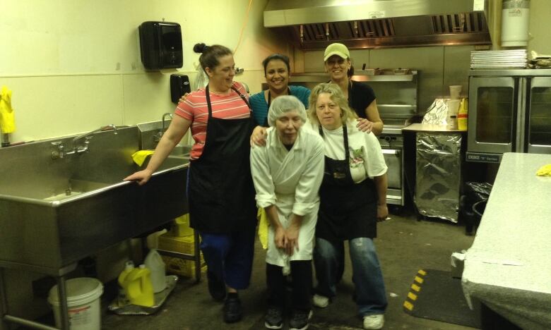 A group of women pose for a picture in a kitchen.