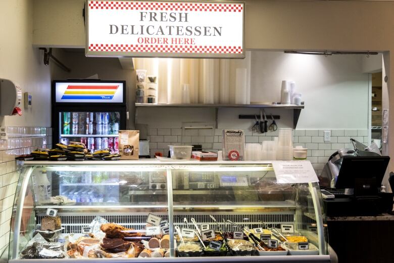 A delicatessen display with a soda machine and cash register next to it.