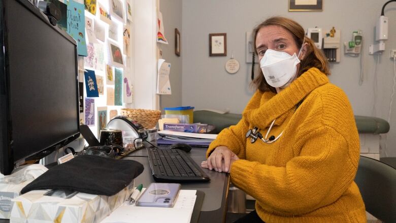 Dr. Nili Kaplan-Myrth wears a mask as she sits at a desk and computer.