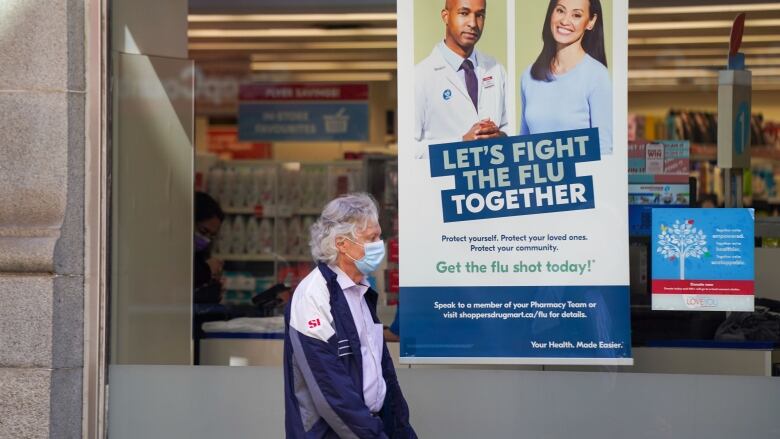 A man walks by a pharmacy sign for flu vaccinations.