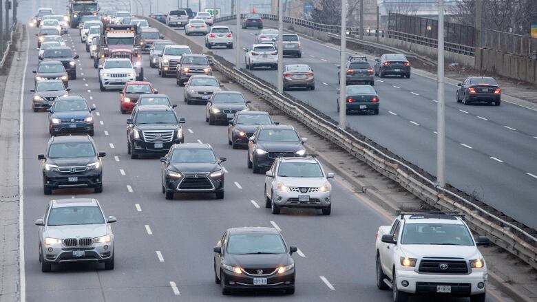 A thick pack of cars travel on an elevated expressway.