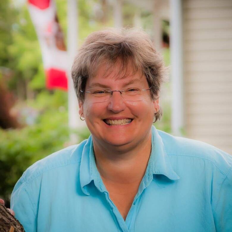 A smiling middle aged woman with short light brown hair and glasses.