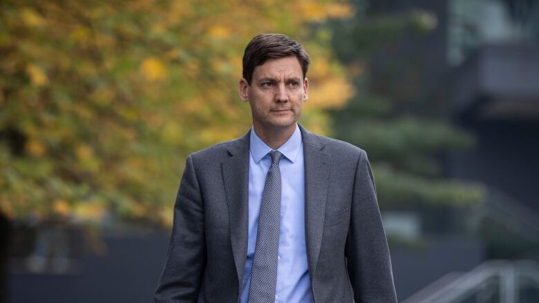 David Eby, a white man wearing a suit, walks through a plaza.