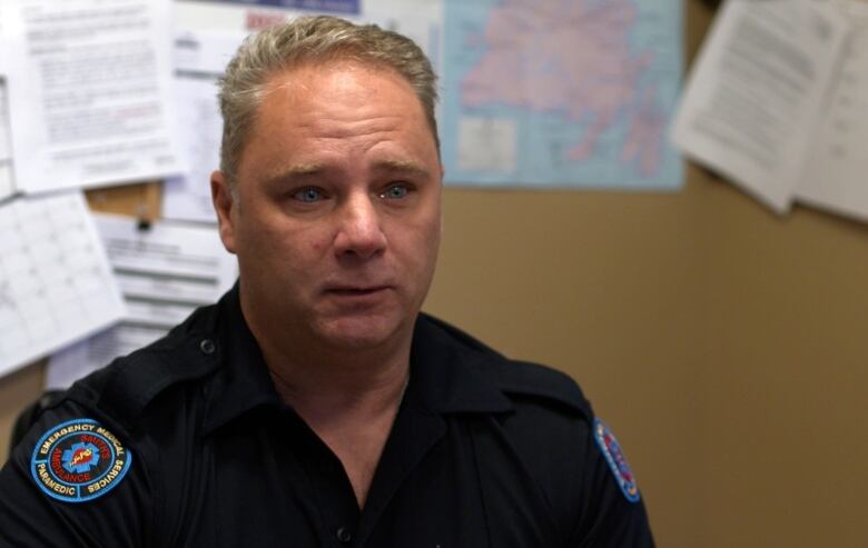 A paramedic sits in an office looking emotional.