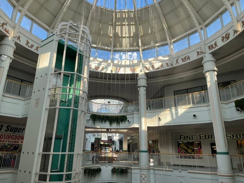 The inside of a shopping mall as light pours in through the open ceiling. 