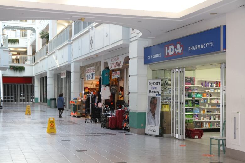 An empty mall hallway, with one pharmacy open. 